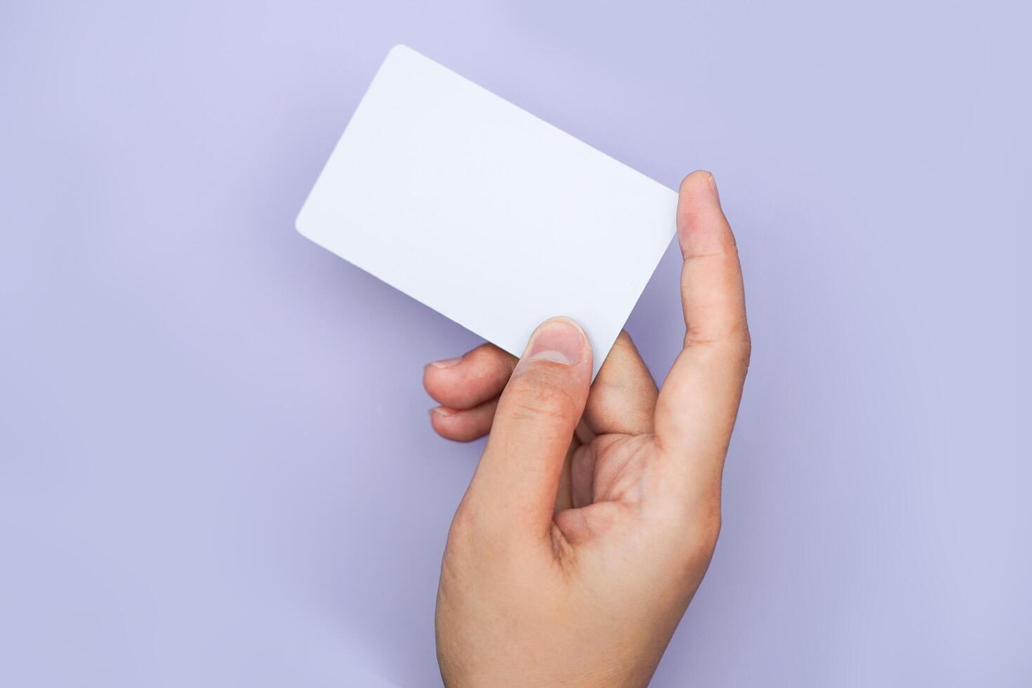 a right hand holding an empty white space on a lavender background. a mockup that is suitable for business or identity mockup use. photo