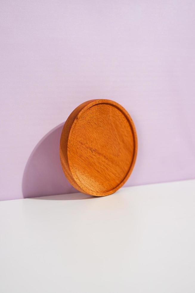 a standing wooden placemat on the lavender wall. a studio shot of the organic utensils. suitable for advertisement. photo