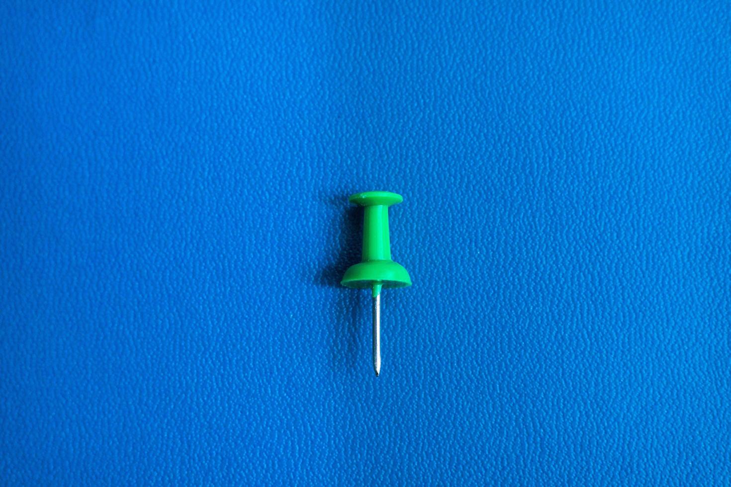 a thumbtack on a blue background. realistic pushpin for pinning paper and notes on board. office stationery collection. photo