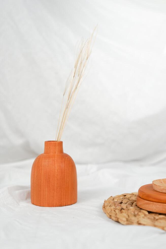 ambientación minimalista de la toma de plataforma del producto para exhibir un jarrón rústico con plantas secas en él. el arreglo del jarrón de madera en blanco. foto