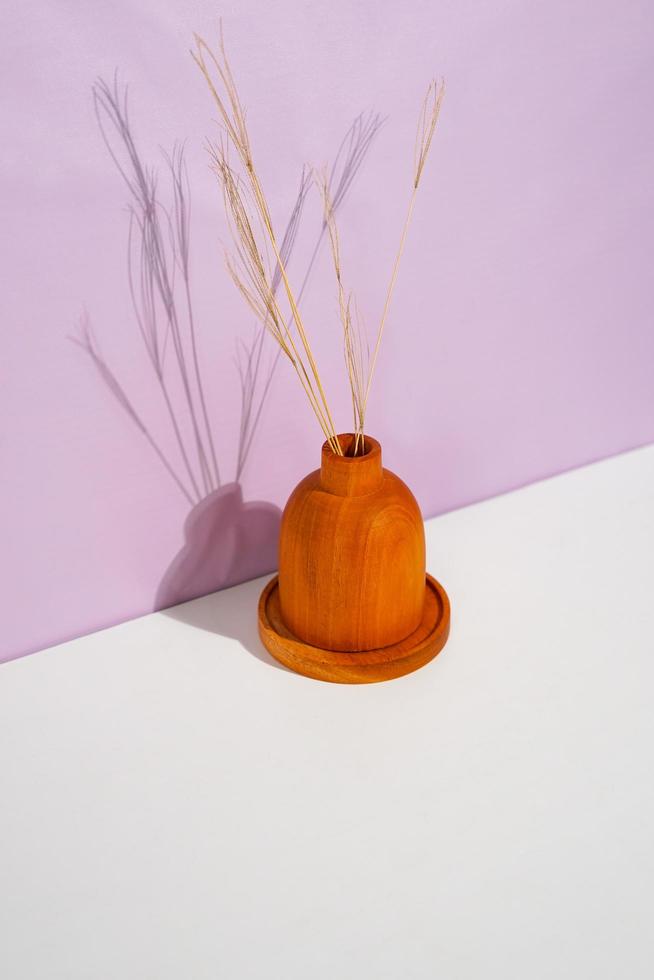 a wooden decorative bottle with a dried plant inside on top of the stacked placemats. a studio shot of the organic utensils. suitable for advertisement. photo