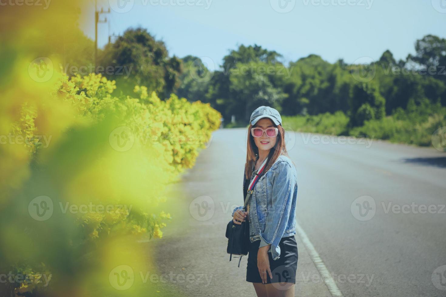 portrait of beautiful woman wearing sunglasses standing on road side photo