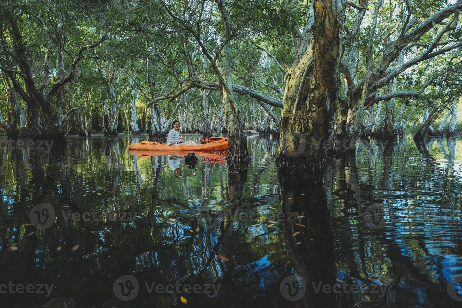 Mujer navegando en kayak de mar en el canal del bosque de manglares foto