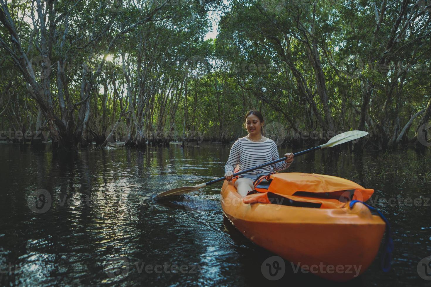 Mujer joven asiática navegando en kayak en el río manglar foto