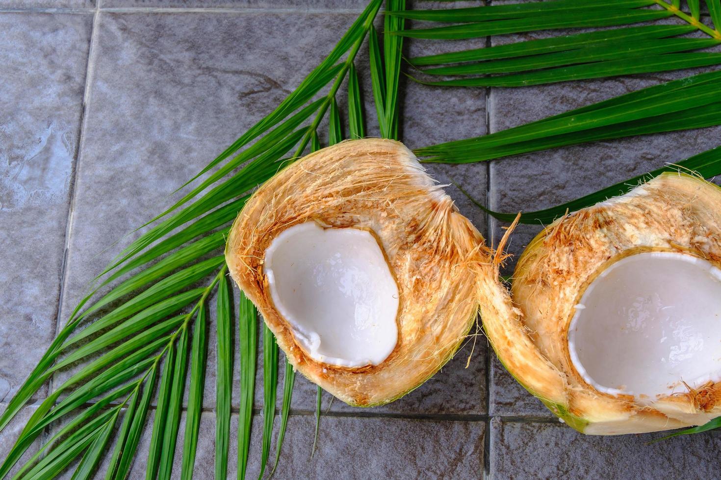 fruta de coco verde fresca cortada por la mitad y hojas de coco foto