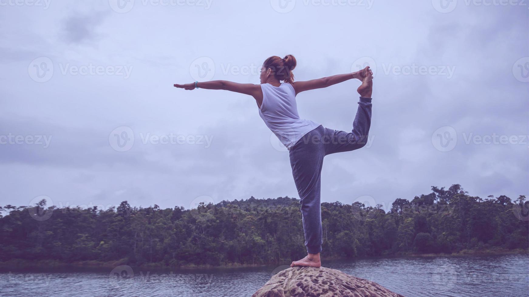 las mujeres asiáticas se relajan en las vacaciones. jugar si yoga. en las rocas en medio del agua. foto