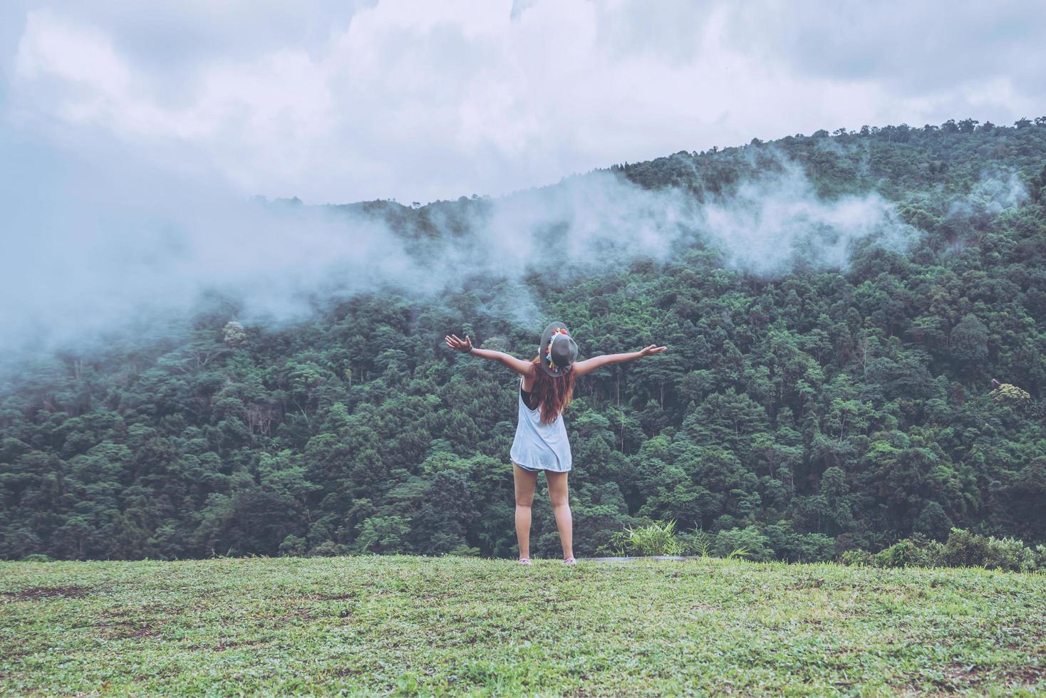 Asian women travel relax in the holiday. Standing hands on wild nature wood on the mountain. photo