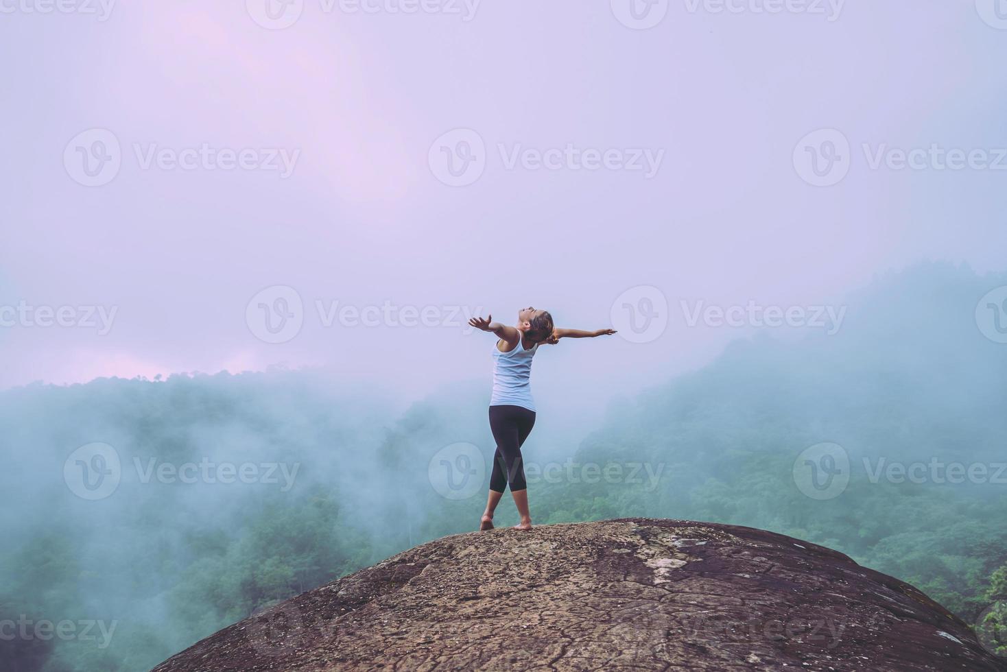 Asian women travel relax in the holiday.  Standing hands on a rocky cliff. Wild nature wood on the mountain. photo