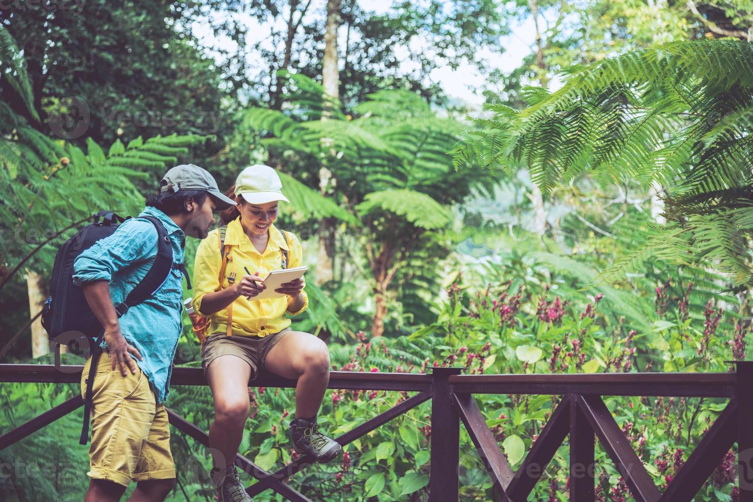 Asian couple travel nature walking relax and studying nature in the fores. photo