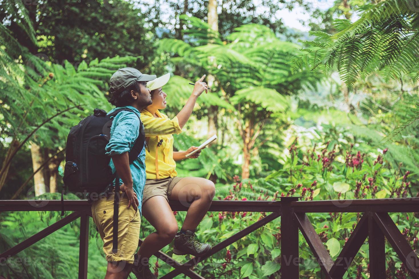 Asian couple travel nature walking relax and studying nature in the fores. photo