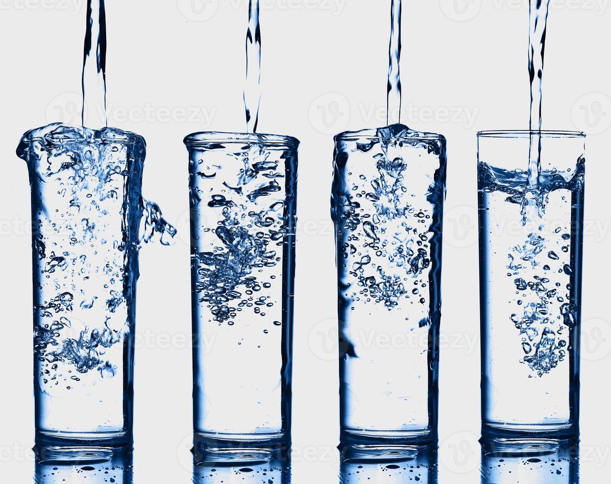 Resumen de salpicaduras de vidrio de botella transparente de agua azul con burbujas en blanco. foto