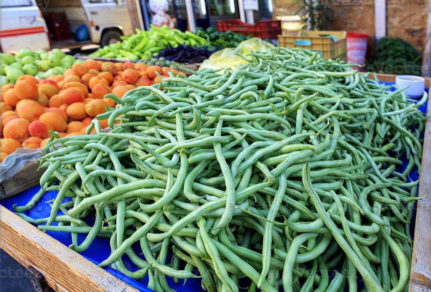 String beans, asparagus, apricots, pears, peppers, plums are sold on the counter. photo