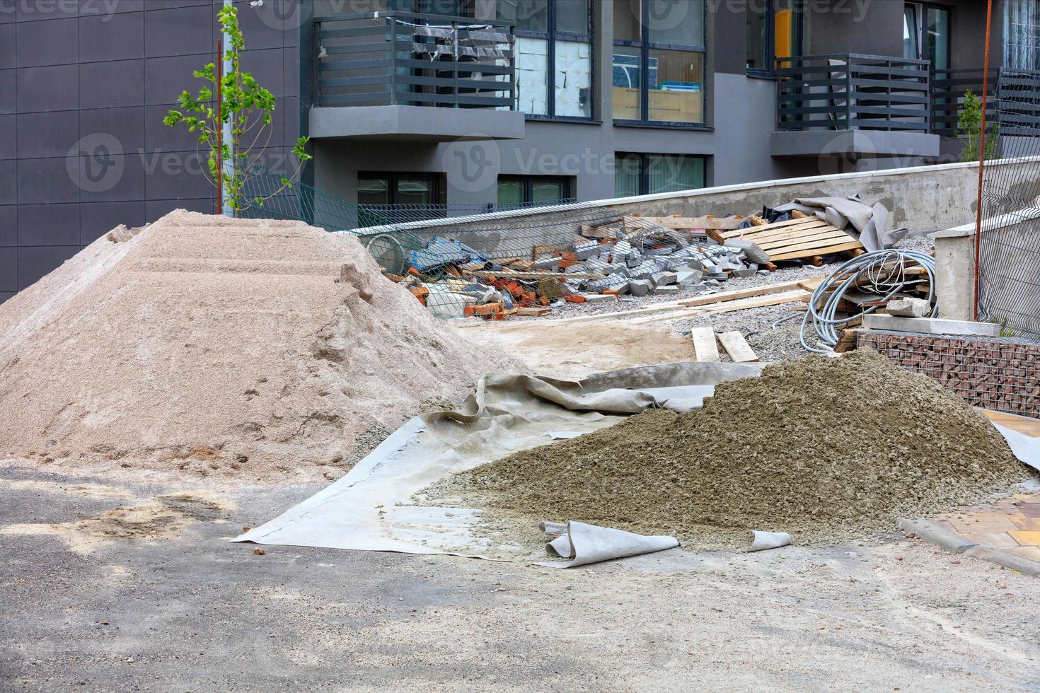 un sitio de construcción con un montón de arena y cemento tamizados en el fondo de un nuevo edificio residencial al aire libre. foto