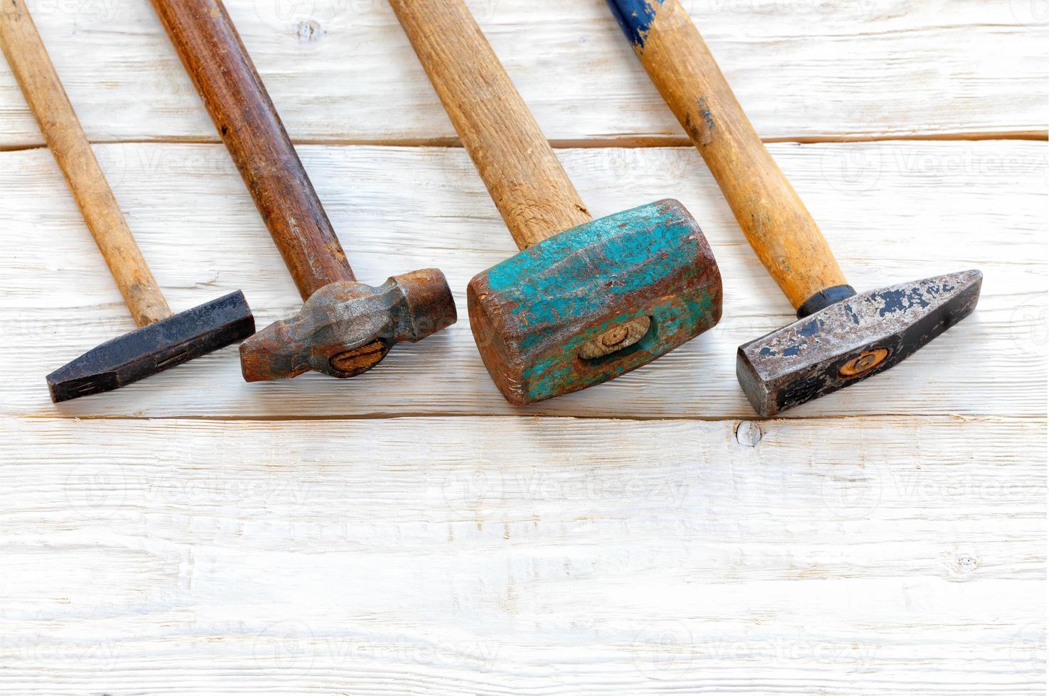 Set of old iron hammers on a white wooden table. photo