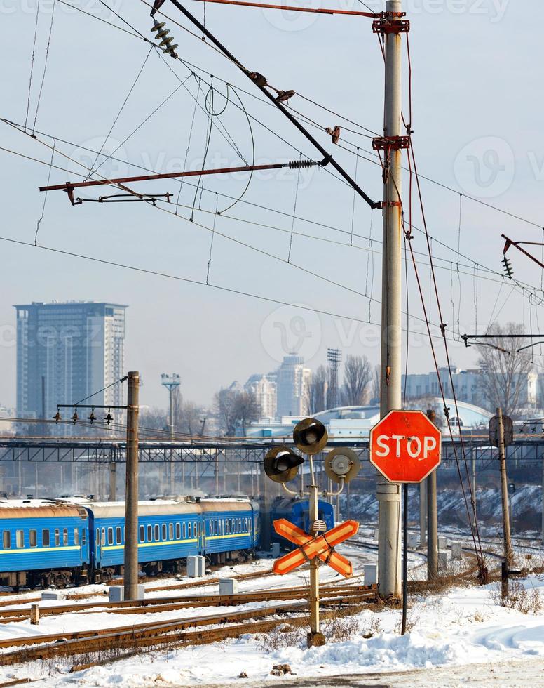 Red stop sign at the railway crossing at the entrance to the city against the background of the winter season. photo