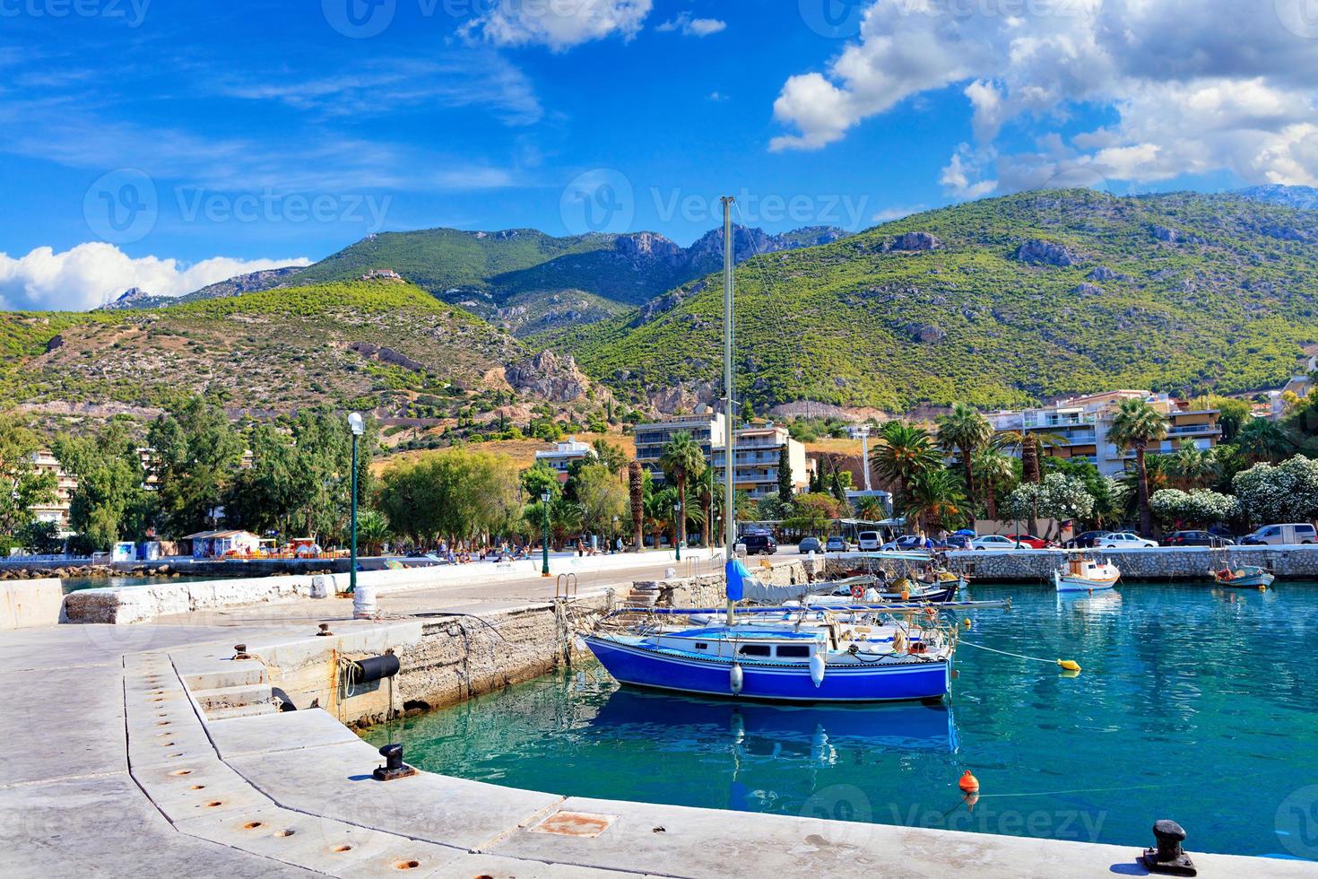 vista panorámica de la bahía y el muelle de Loutraki, Grecia, donde pequeñas goletas de pesca, yates, botes y botes amarrados en las cristalinas aguas del mar jónico. foto