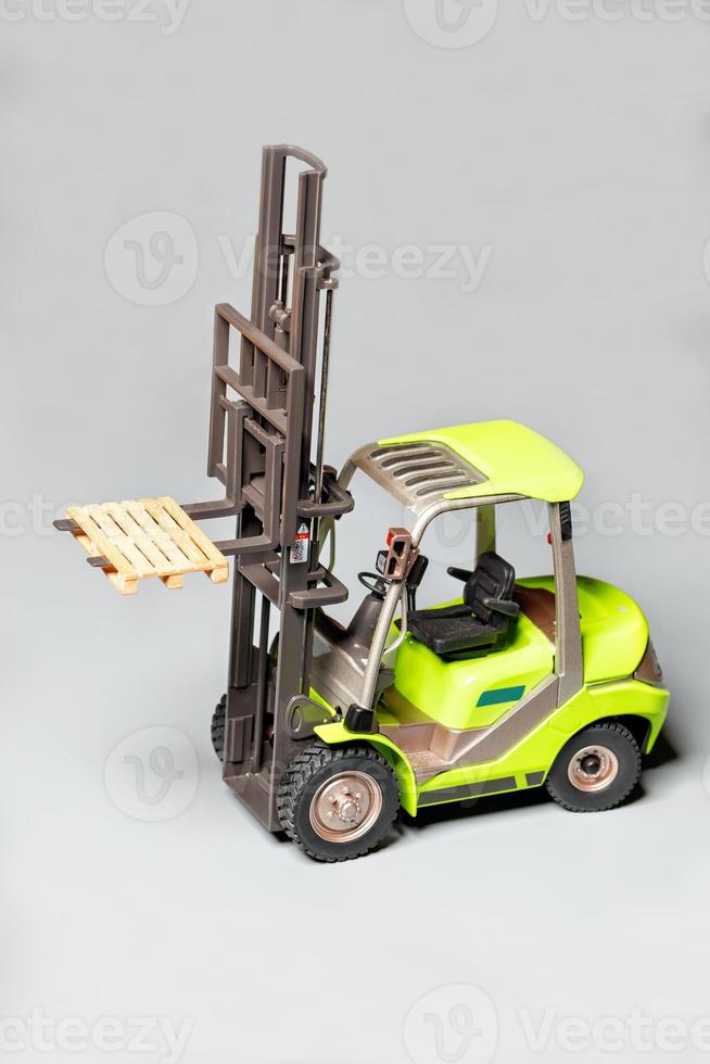 Toy model of an industrial pallet loader on a light gray background. photo