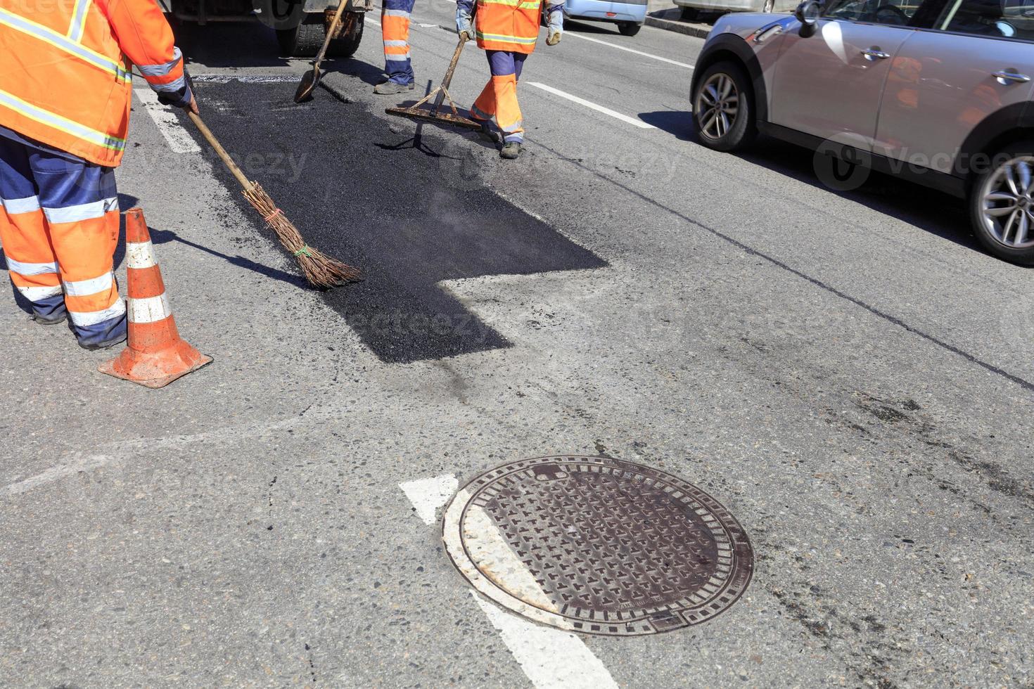 The working team smoothes hot asphalt with shovels, level and broom by hand when repairing the road. photo