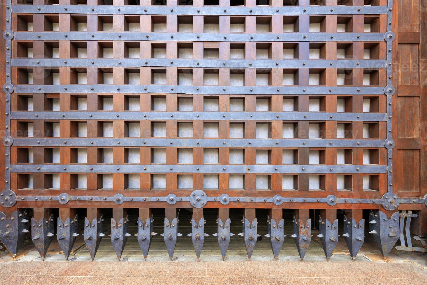 Las antiguas puertas de madera antiguas están cubiertas con barras forjadas y puntas dentadas al final. foto