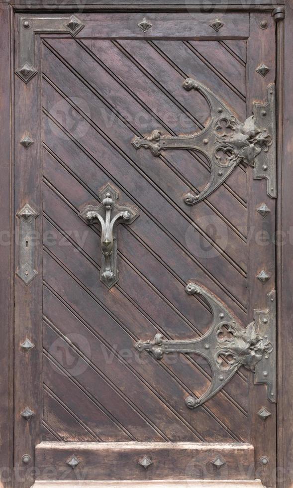 Ancient antique wooden doors with wrought iron loops and cross bars. photo