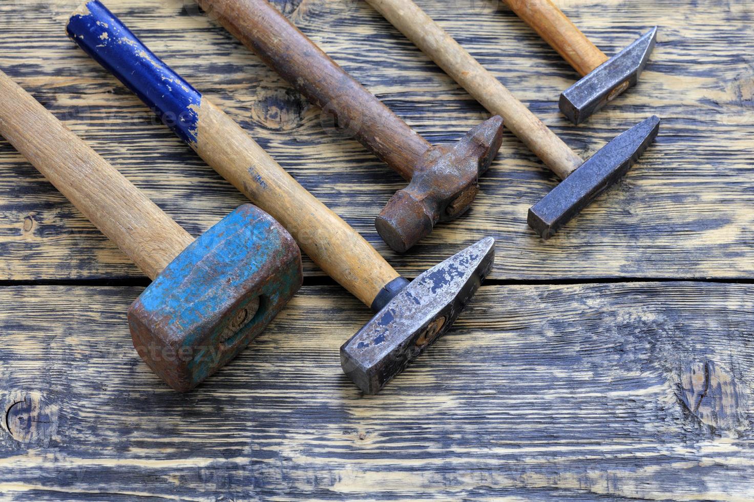 Old iron hammers lie on a wooden table. photo