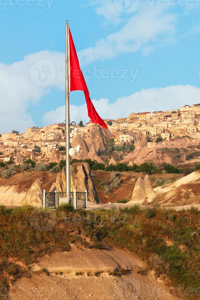 Las grandes torres de la bandera nacional de Turquía sobre el antiguo pueblo de Uchisar en Capadocia. foto