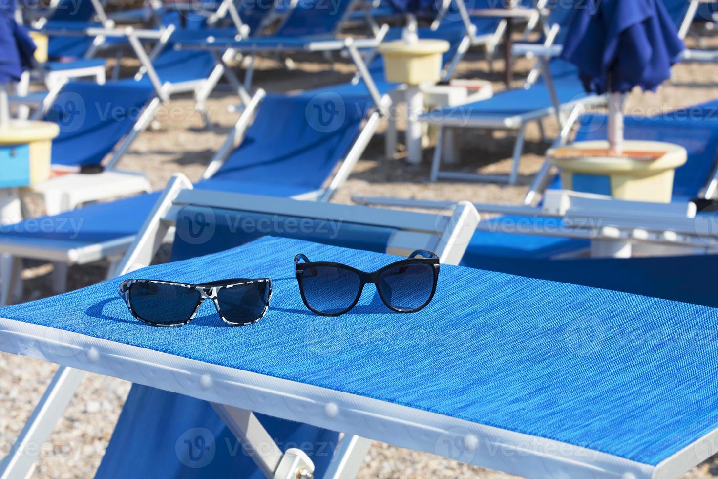 gafas de sol en una chaise longue azul brillante foto