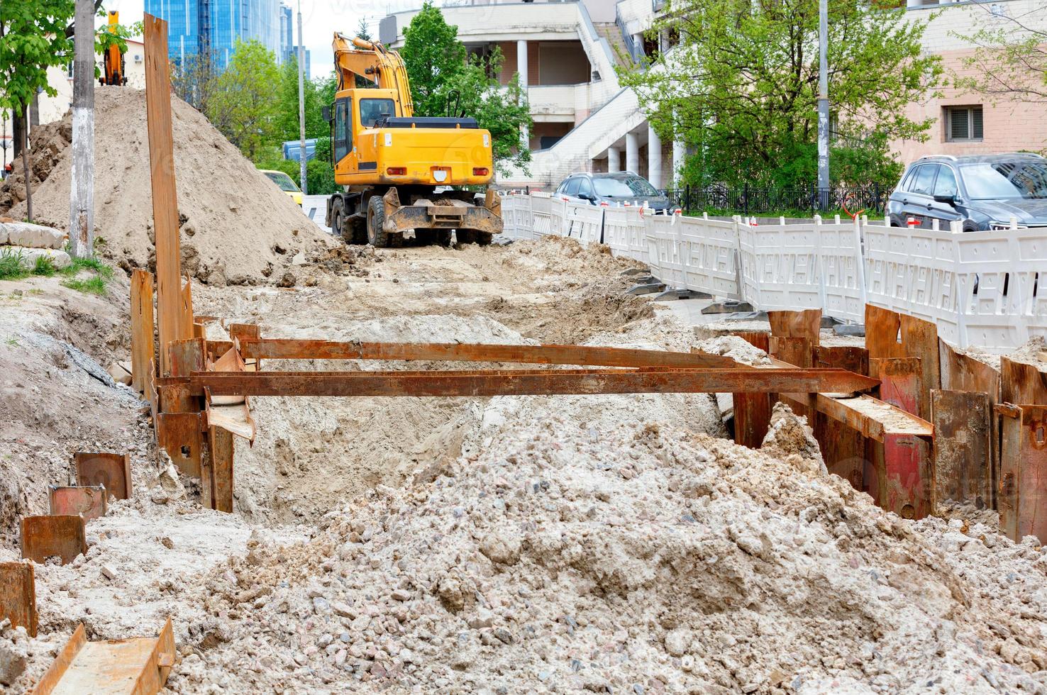 Repair of the city heating main on the roadway, metal piles driven into sandy soil. photo