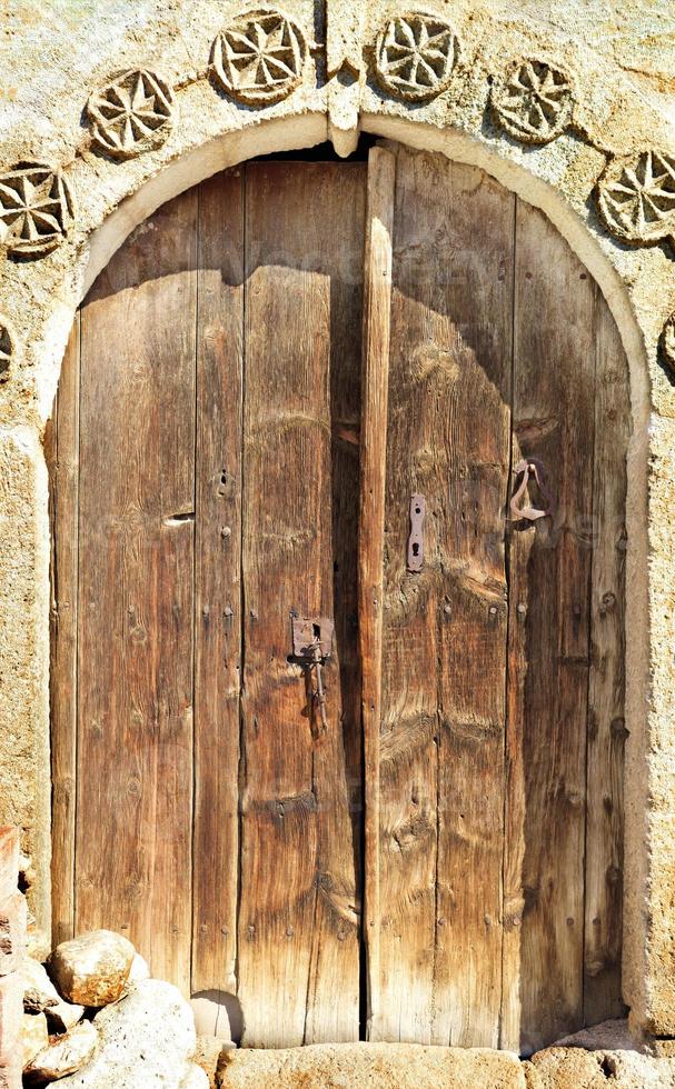 Puertas de madera arqueadas antiguas con un patrón de piedra y una cerradura de metal en el medio. foto