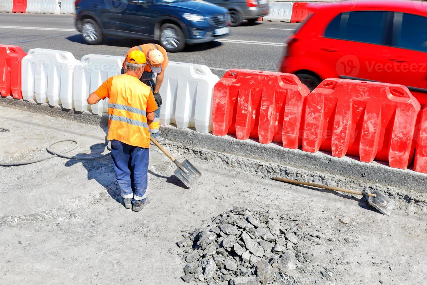 Road workers knock down old concrete during road repairs and shovel a work area. photo