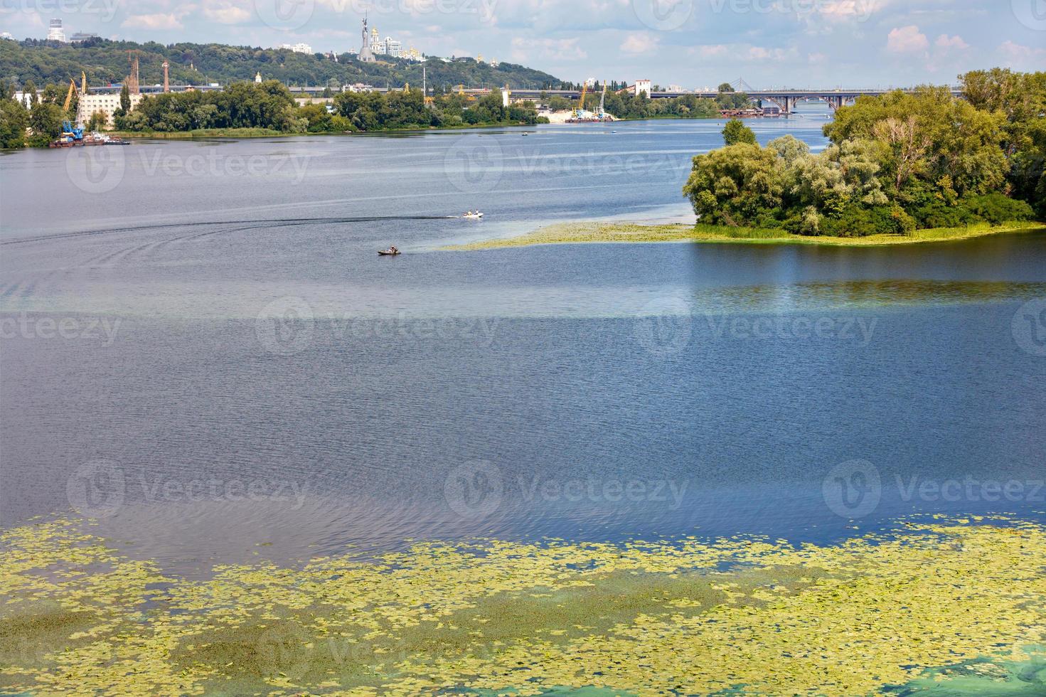 The picturesque natural landscape of the Dnipro River in the middle of summer with river lilies floating on the water in the foreground. photo