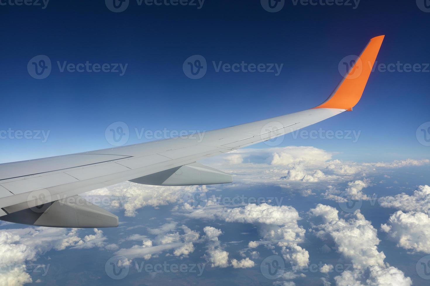 Wing of a flying airplane in a blue sky photo