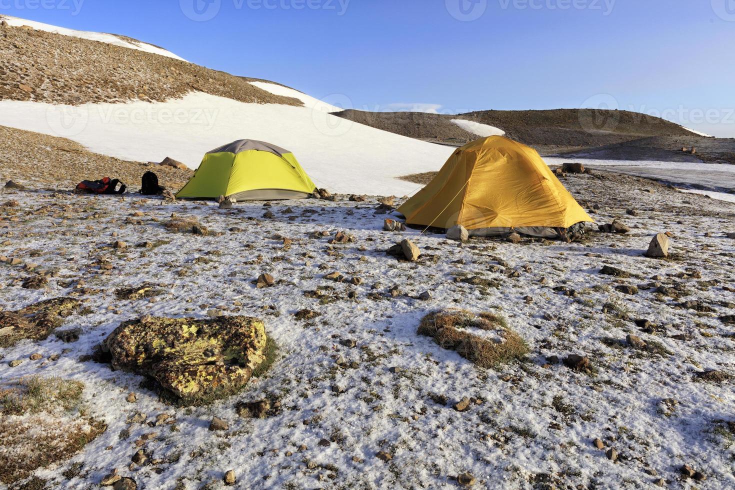 Tents of tourists are located at the foot of a snow-covered mountain. photo