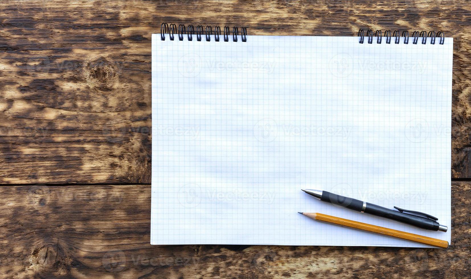 Empty notebook with a pencil and black pen on an old textural wooden surface. photo