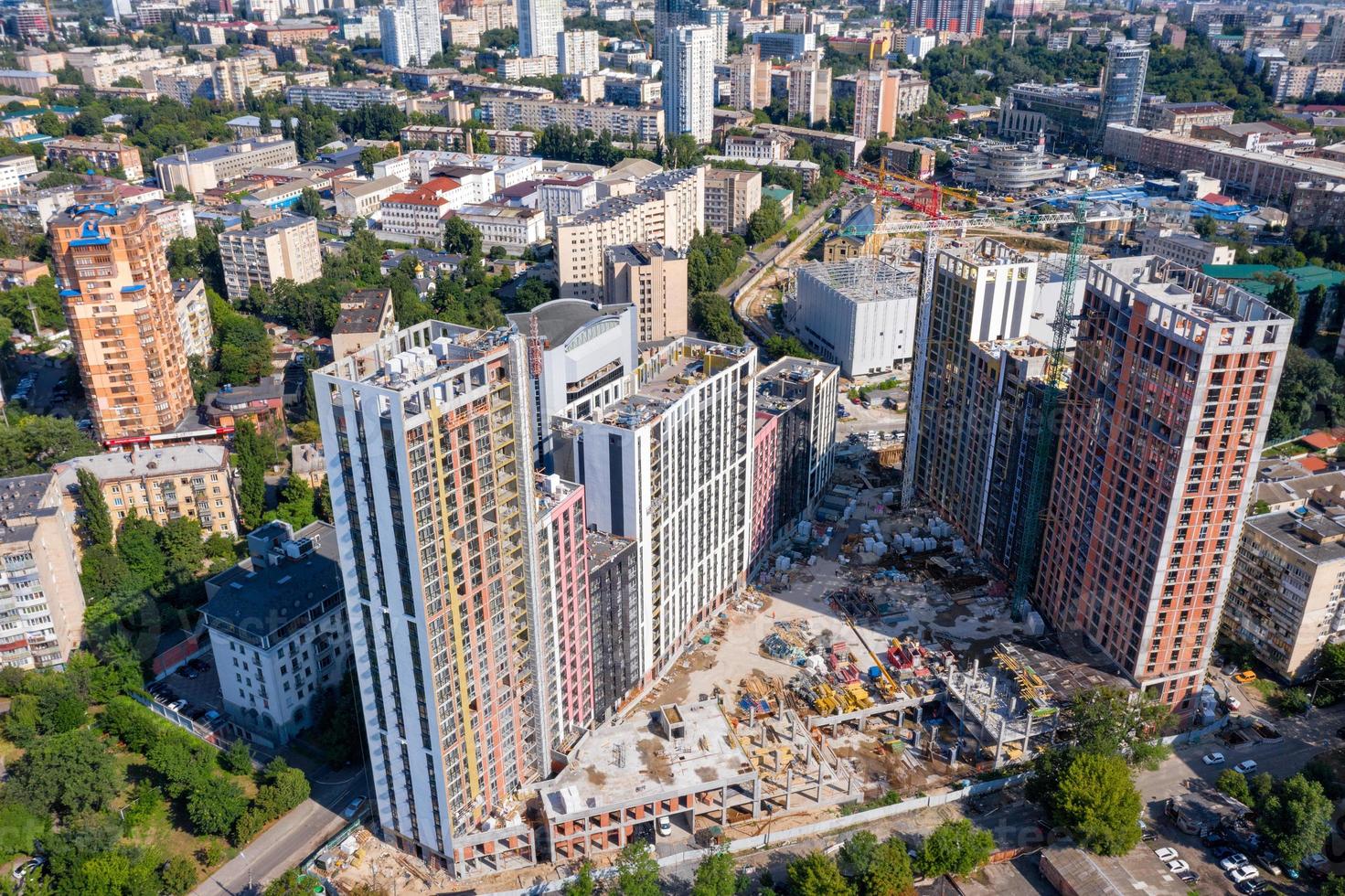 En la fotografía aérea, la luz del sol ilumina un sitio de construcción entre áreas residenciales urbanas en el verano. foto