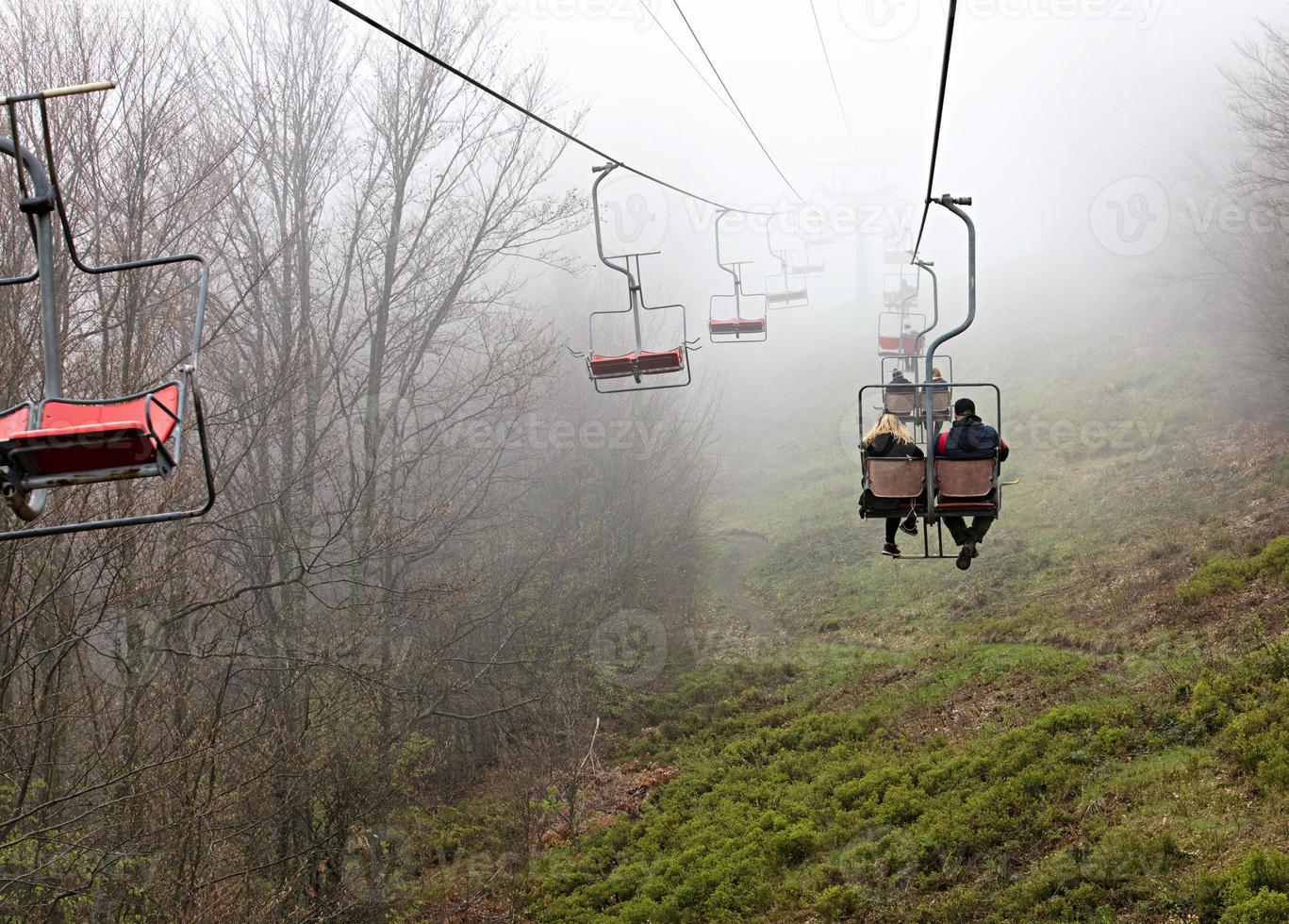 Mountain lift carries tourists to the misty mountain photo