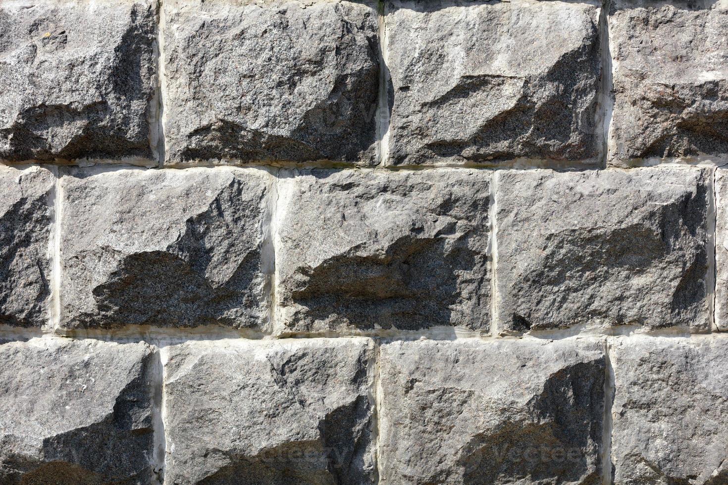 Muro de piedra de grandes adoquines de granito gris, primer plano. foto