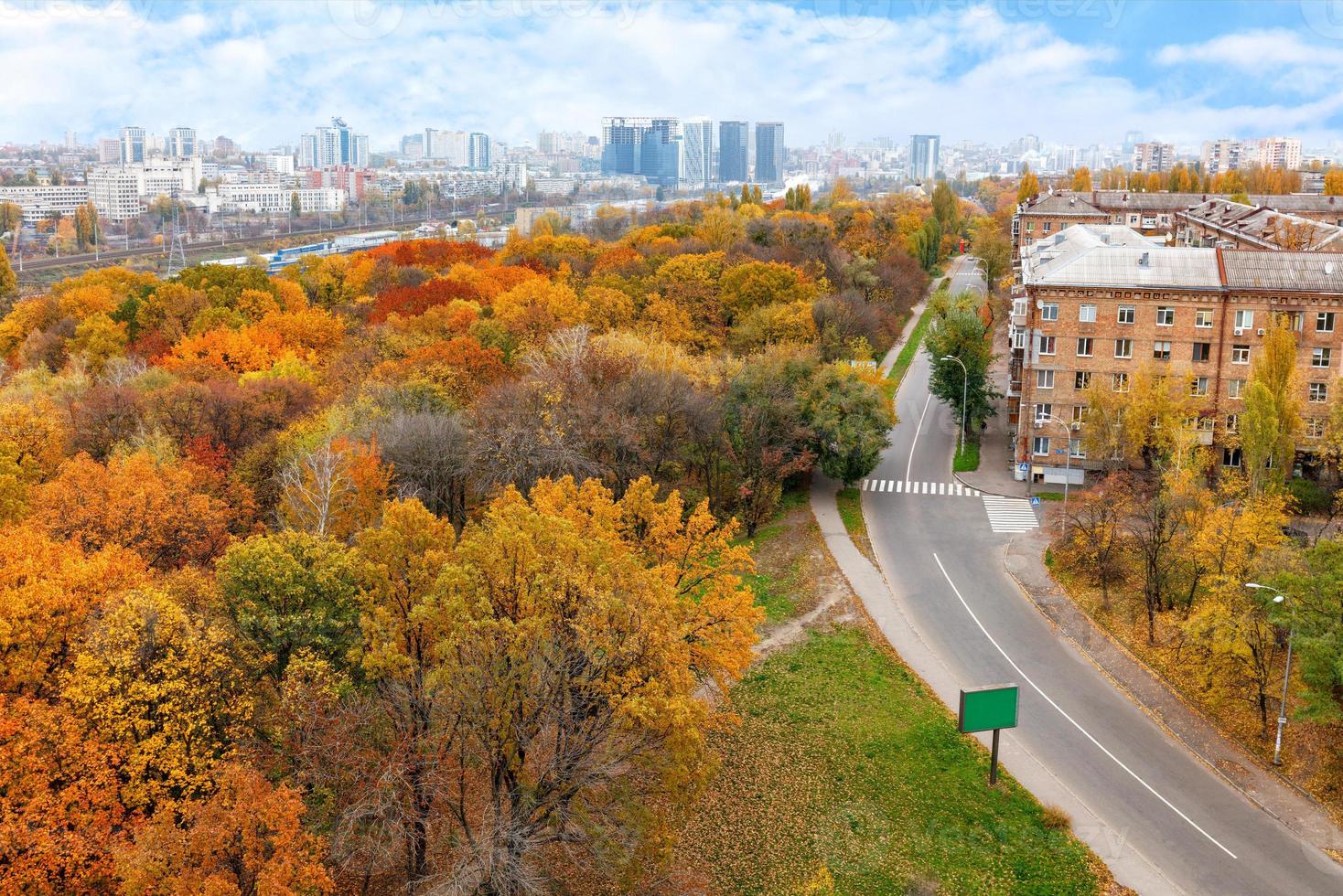 Bright orange foliage of the city park in the autumn landscape of the city, view from the top. photo