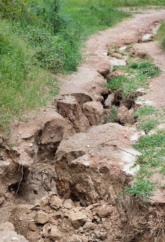 Severe erosion of soil washed out after rain streams on the slope. photo