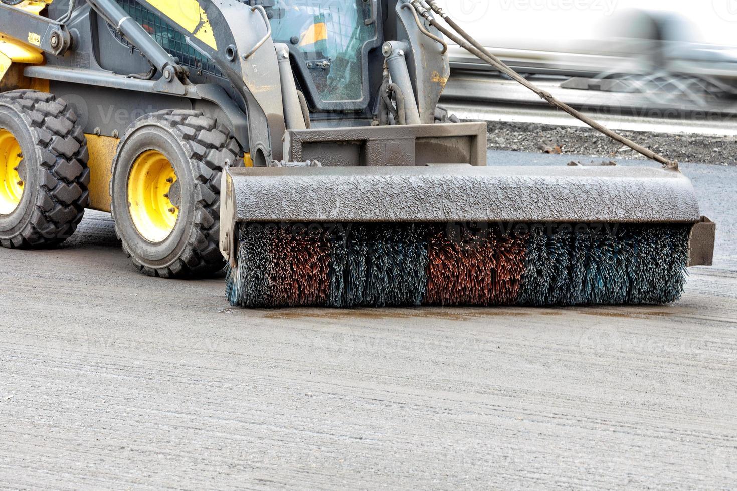 The compact road grader removes dirt from the road with a hydraulic nylon brush. Copy space. photo