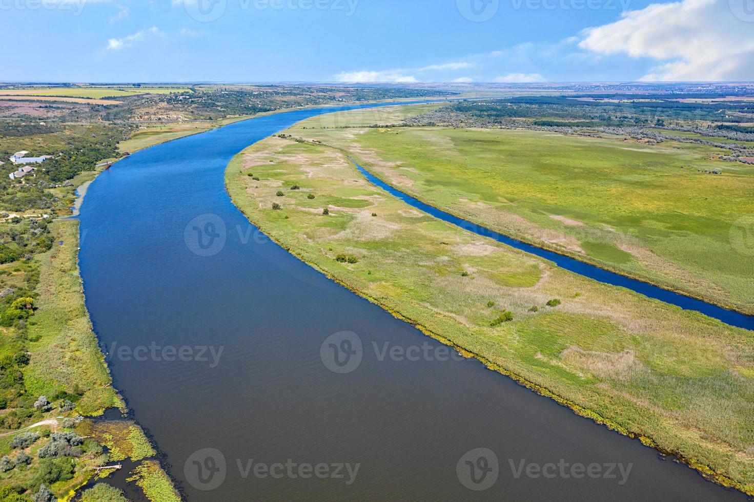 A beautiful bend of a wide river among green meadows on a sunny summer day from a bird's eye view. photo