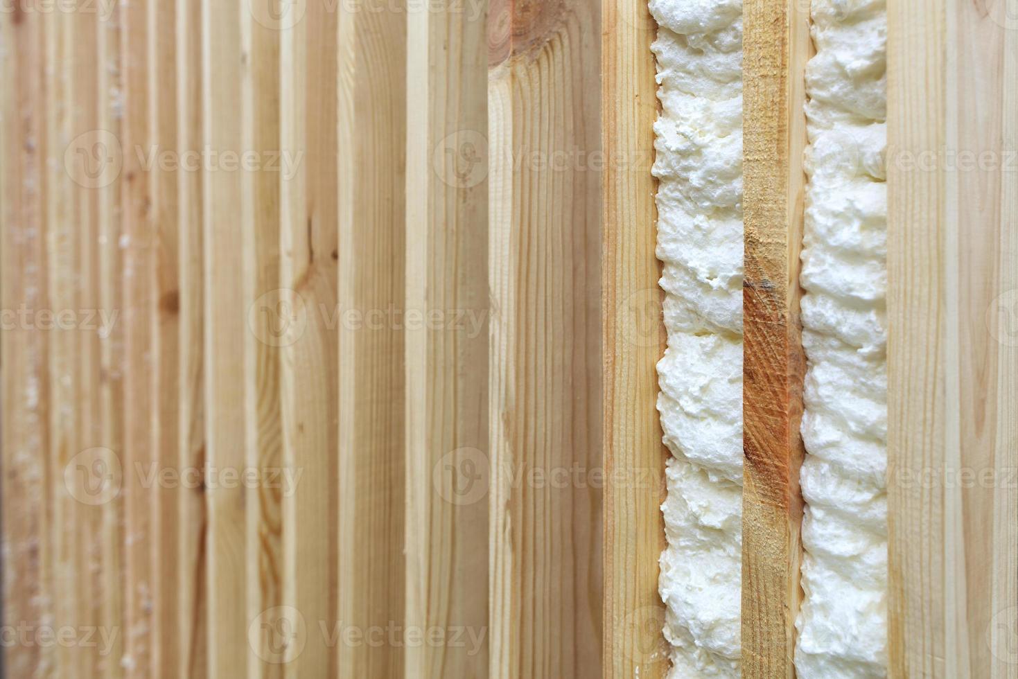 An example of filling the gap between vertical wooden planks with building foam. photo