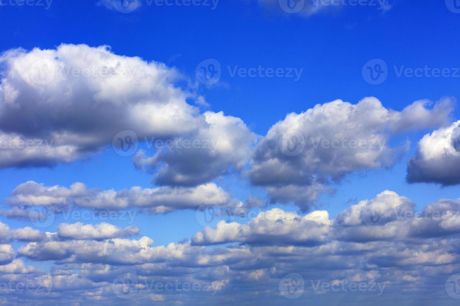 White and gray lush clouds cover a bright saturated blue sky. photo