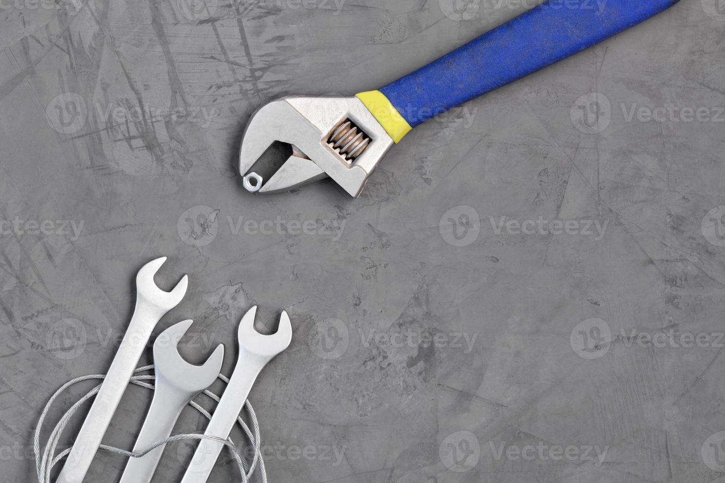 Adjustable wrench feeds a nut new wrenches on a background of gray concrete. The concept of training and development. photo