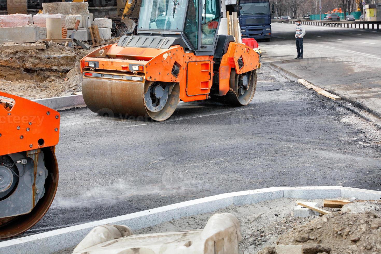 Two large vibratory road rollers are working on a construction site, compacting fresh asphalt. photo