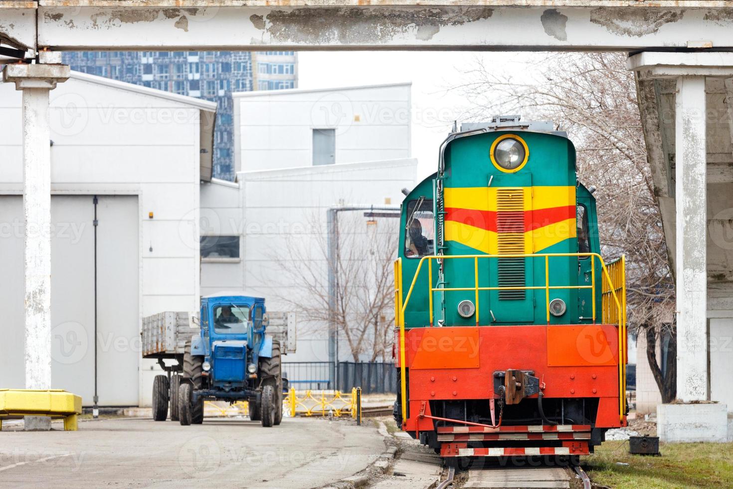 Old, but in working order, diesel locomotive tractor and wheeled tractor leave the depot. photo