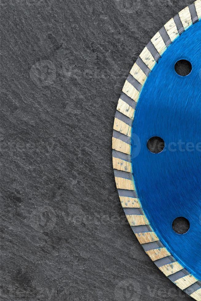 Fragment of a blue diamond cutting wheel on a gray granite background. Copy space. Vertical image. photo