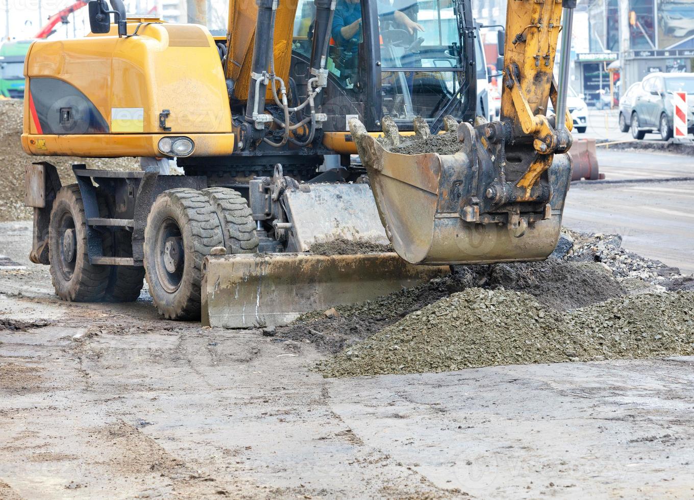 A heavy road excavator smooths a pile of rubble with a bucket at a construction site. photo
