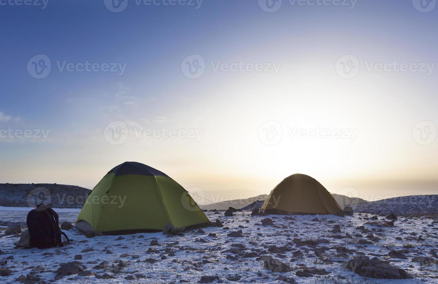 Backpacks and tents of tourists are located on top of the mountain photo