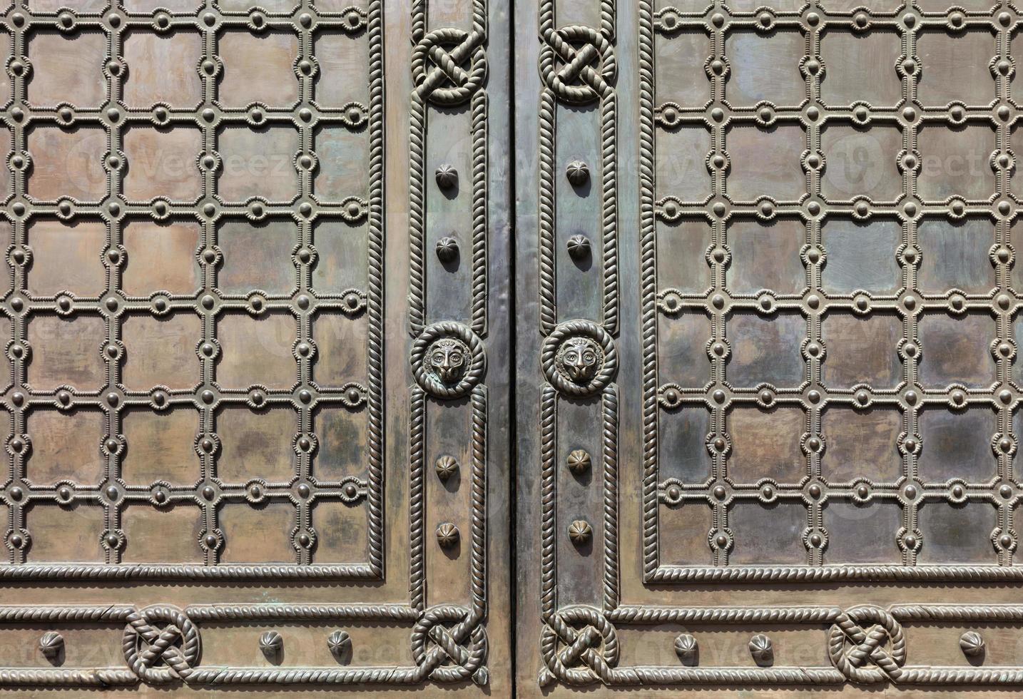 Antique metal doors covered with wrought iron grille and patterned pattern. photo